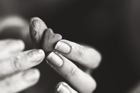 Heart made of potters clay in the hands of a master potter. Love concept. Black and white color