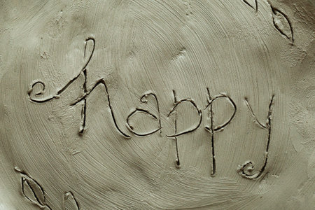 Potter inscription happy on a wet clay plate. Grey modelling clay background and textureの写真素材