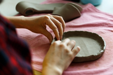 Closeup Image of Female Hands Works with Clay Makes Future Ceramic Plate, Classes of Hand Building in Modern Pottery Workshop, Creative People Handcrafted Design.の写真素材
