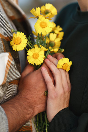 Couple holding bouquet of yellow daisies in sunset sunlight, summer vacation.の写真素材