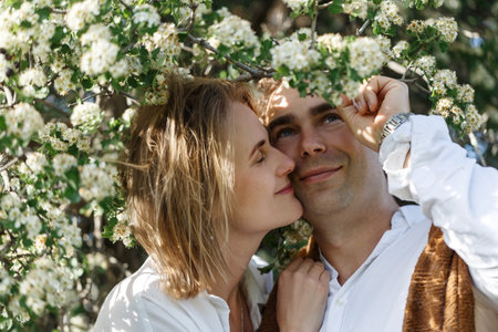 Close-up portrait of happy couple in the tree flowering, closeup, young woman and man looking at the camera.の写真素材