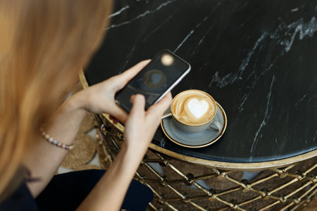 Woman taking photo of coffee with smartphone. top viewの写真素材