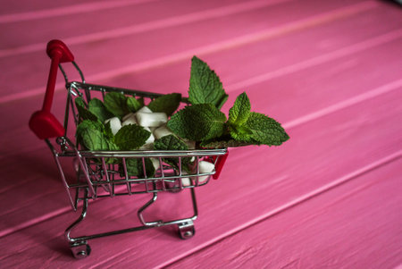 mint gum, mint and small cart on pink wooden background 2の写真素材