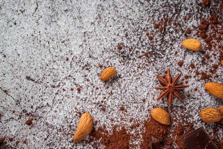 natural cocoa powder, chocolate, star anise, raw almonds scattered on a gray neutral concrete...