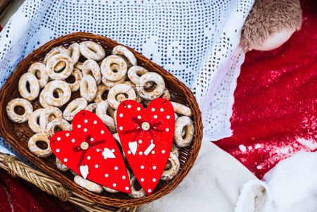 red hearts and bagels in a basket on a red blanket in the winter in the snow