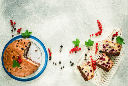 sliced pieces of homemade berry pie lie on a white wooden board with black and red currants on a...