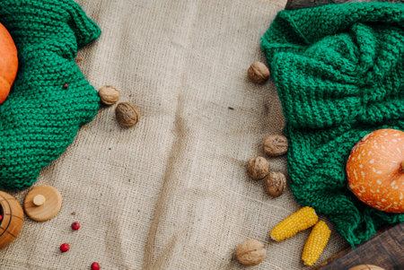 autumn harvest, orange pumpkin, nuts, corn, red berries lie on a tablecloth on a green knitted fabricの写真素材