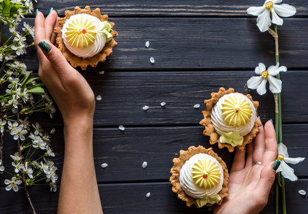 lemon muffins in hands against a background of white spring flowers and a black wooden table