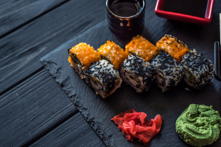 set of sushi, pickled ginger, soy sauce on a black wooden backgroundの写真素材