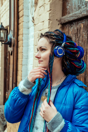 girl with blue dreadlocks and blue clothes listening to music on headphonesの写真素材