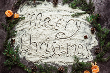 inscription merry christmas drawn on flour in a circle of fir branches and tangerine 1の写真素材