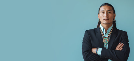 A Native American man wearing business attire and traditional jewelry, standing confidently against a blue background.の素材