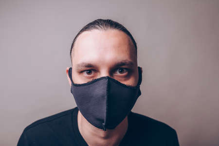 man in black hand made mask on gray background closeupの写真素材
