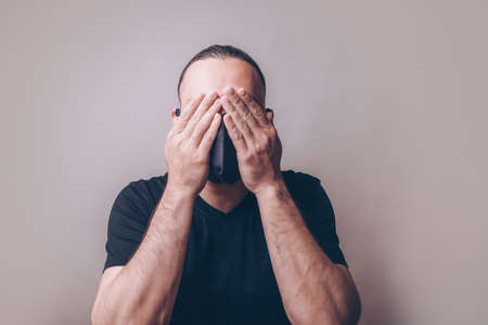 A man in a mask hiding his faceの写真素材