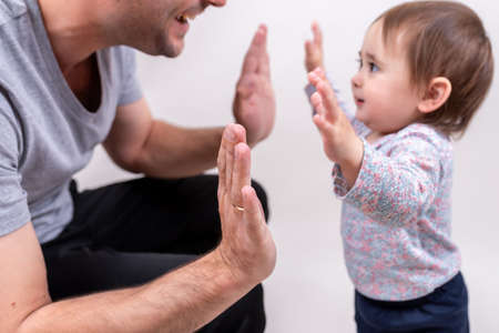 Good father clapping hands with his daughter on Father's Day holiday. Friendship with parent and kidの写真素材