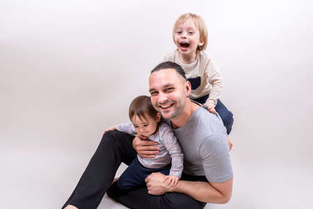 Young father playing with happy laughing kids sitting on the floor during Father's dayの写真素材