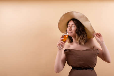 Beautiful woman in straw hat tastes aperol cocktail in pillow challenge wearの写真素材