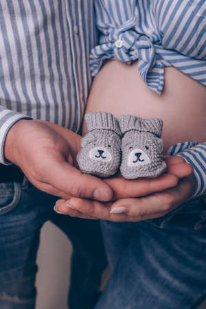 Pregnant woman and her husband holding first baby's bear booties close up verticalの写真素材