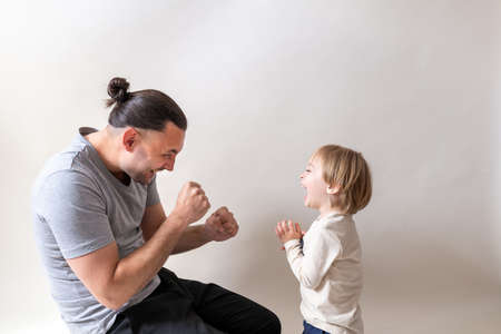 Young father boxing with his little son on white studio backgroundの写真素材