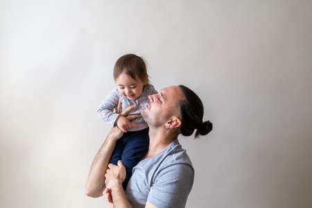 Young long hair father holding daughter on his shoulder. Captured on white studio backgroundの写真素材