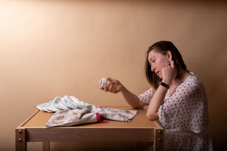 Tired and sleepy mother looks at the baby bottleの写真素材