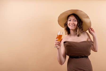 Young woman in straw hat with orange drink dreaming about vacation on seaの写真素材