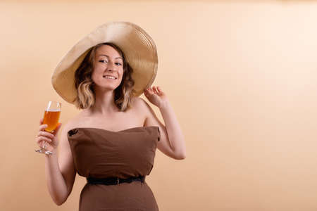 Beautiful woman in straw hat with orange drink dreams about summer vacationの写真素材