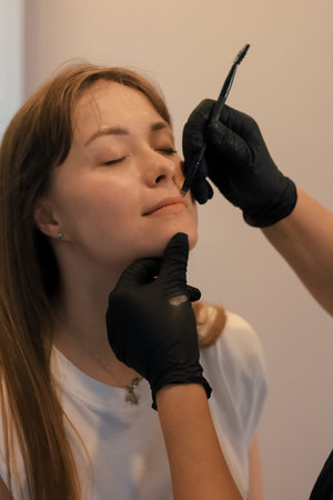 Young woman having permanent makeup on lips in beautician salon.