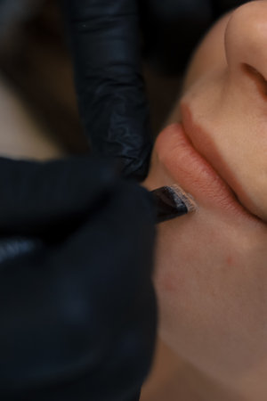 Young woman having permanent makeup on lips in beautician salon.の写真素材
