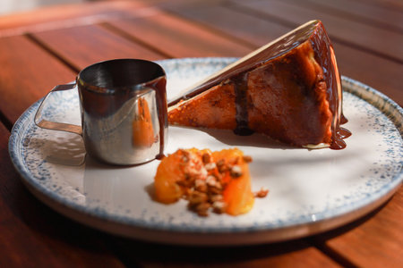 Dessert San sebastian Cheesecake on white plate with chocolate and orange, wooden tableの写真素材