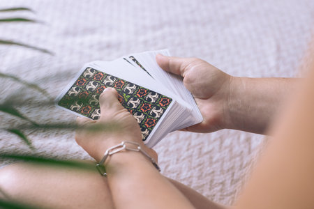 Young woman lays out tarot cards, tells her own fortune on cards at home on her bed, hands with...