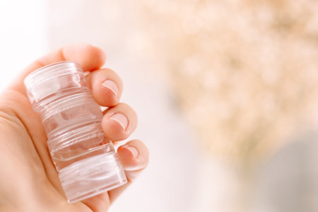 woman hand holds cosmetics jars with produts creams, gels and serum, mini testers, travel kit, skin...