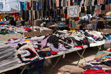 Antalya, Turkey - August 3, 2024 - Bazaar. Turkish stall with various fake designer clothing items. Clothes lying on top of each other. Cheap prices and alternatives to fashion brands. Sales of old collectionsのeditorial素材