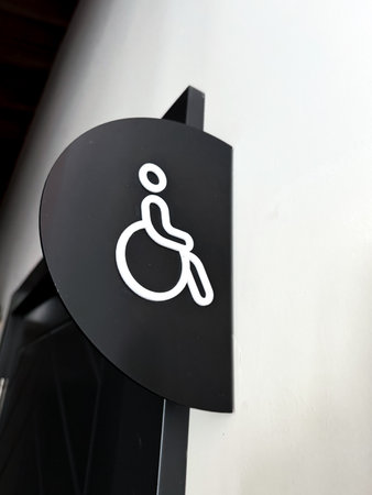 A clearly designed restroom sign features a symbol representing accessibility, specifically intended for individuals with disabilities. This sign is displayed prominently on a wall, ensuring that it is easily visible. The minimalist design uses contrasting colors to highlight the importance of inclusivity in public spaces.の写真素材