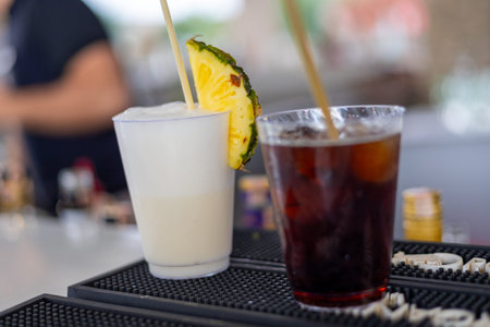Two cocktails are presented at a bar, pina colada and whiskey cola. One drink is white and creamy...