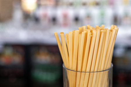 Bamboo straws stand in a glass container in a cafe. Straws are made from natural wheat and cane...