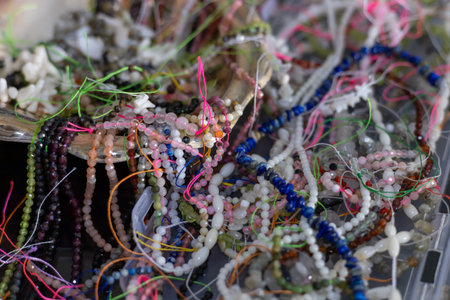 Lithotherapy. Brightly colored natural beads and threads are arranged in a handcrafted bowl. This vibrant collection showcases a variety of designs, reflecting local craftsmanship and creativity.の写真素材