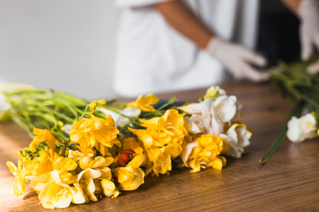 A person holds a stunning bouquet filled with white and yellow flowers, displaying their vibrant colors and fresh appearance. Florist in flowers shop stand on white background, copy space for textの写真素材