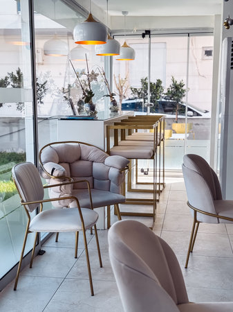 Elegant chairs and a wooden bar create a welcoming atmosphere in a modern cafe. Large windows...