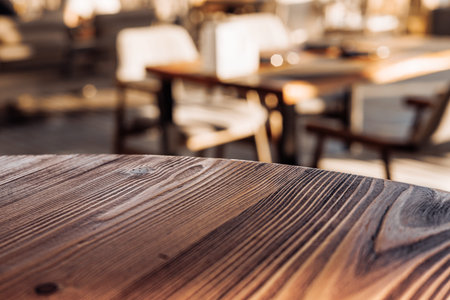 Empty wooden table and blurred background of abstract in front of sunny restaurant or coffee shop...