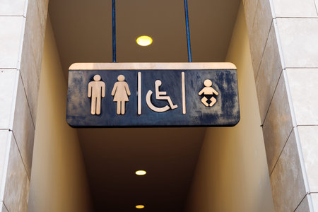 A restroom sign features clear icons for male, female, wheelchair-accessible, and baby changing...