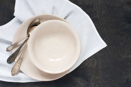 Empty plates and spoons on the wooden table with napkinの写真素材