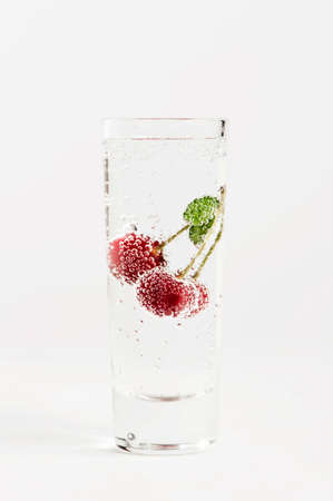 Cherry with bubbles in the glass of waterの写真素材
