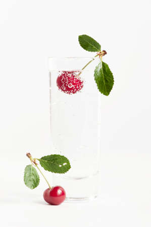 Cherry with bubbles in the glass of waterの写真素材