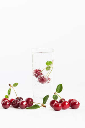 Cherry with bubbles in the glass of waterの写真素材