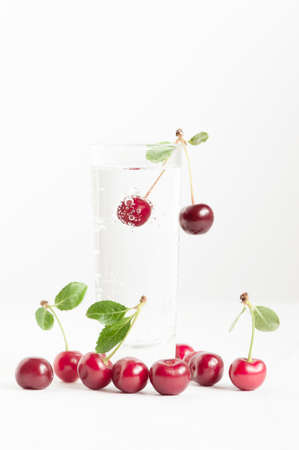 Cherry with bubbles in the glass of waterの写真素材