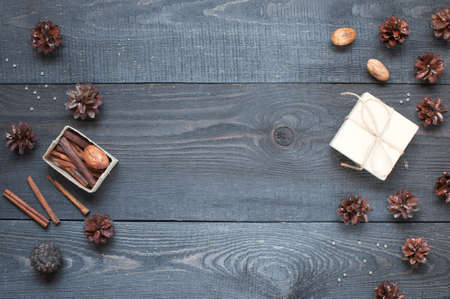 Gift, card, pine cones and cinnamonin on the dark wooden textured tableの写真素材