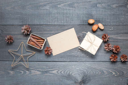 Gift, card, pine cones, metal star and cinnamonin on the dark wooden textured tableの写真素材