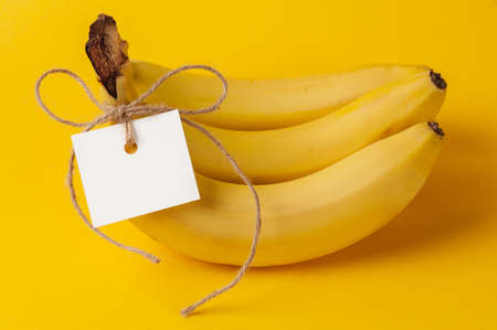 Bunch of ripe bananas with label on the yellow backgroundの写真素材