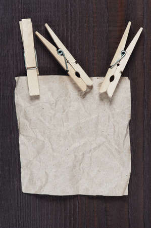 Crumpled sheet of paper with clothespin on the dark wooden tableの写真素材